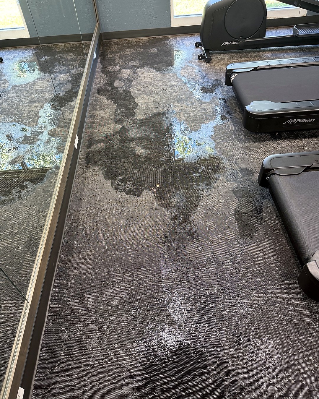 Standing water across the carpeted floor of a hotel fitness area