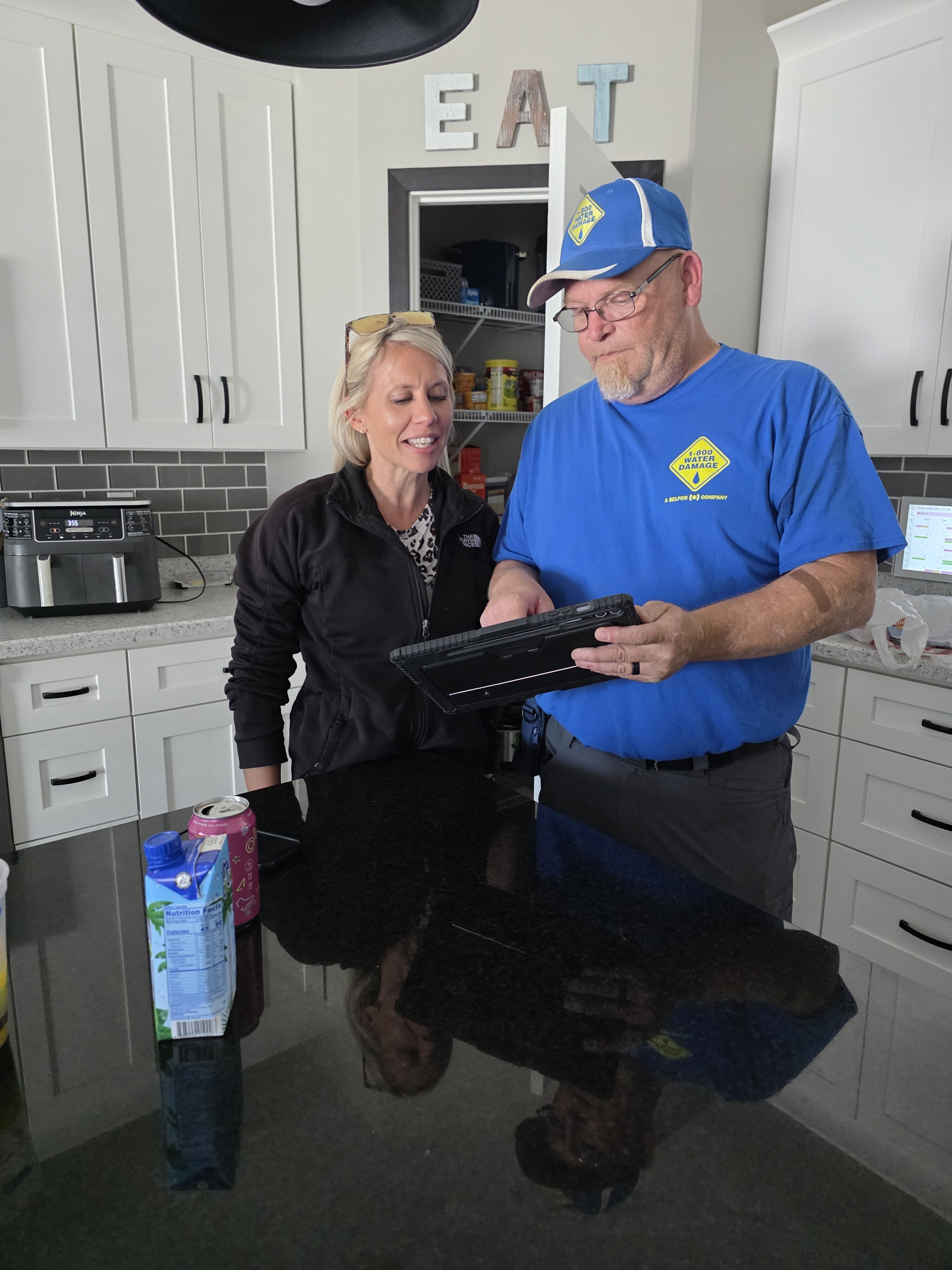 A 1-800 WATER DAMAGE technician reviewing property history with a homeowner before a canine mold screening begins