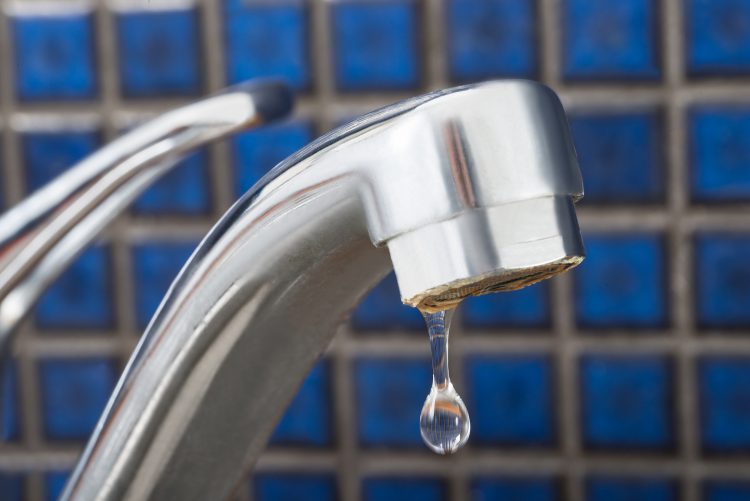 A silver faucet is dripping to avoid burst pipes