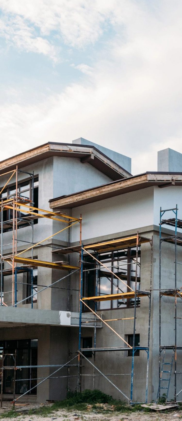 Modern building construction with scaffolding under cloudy sky