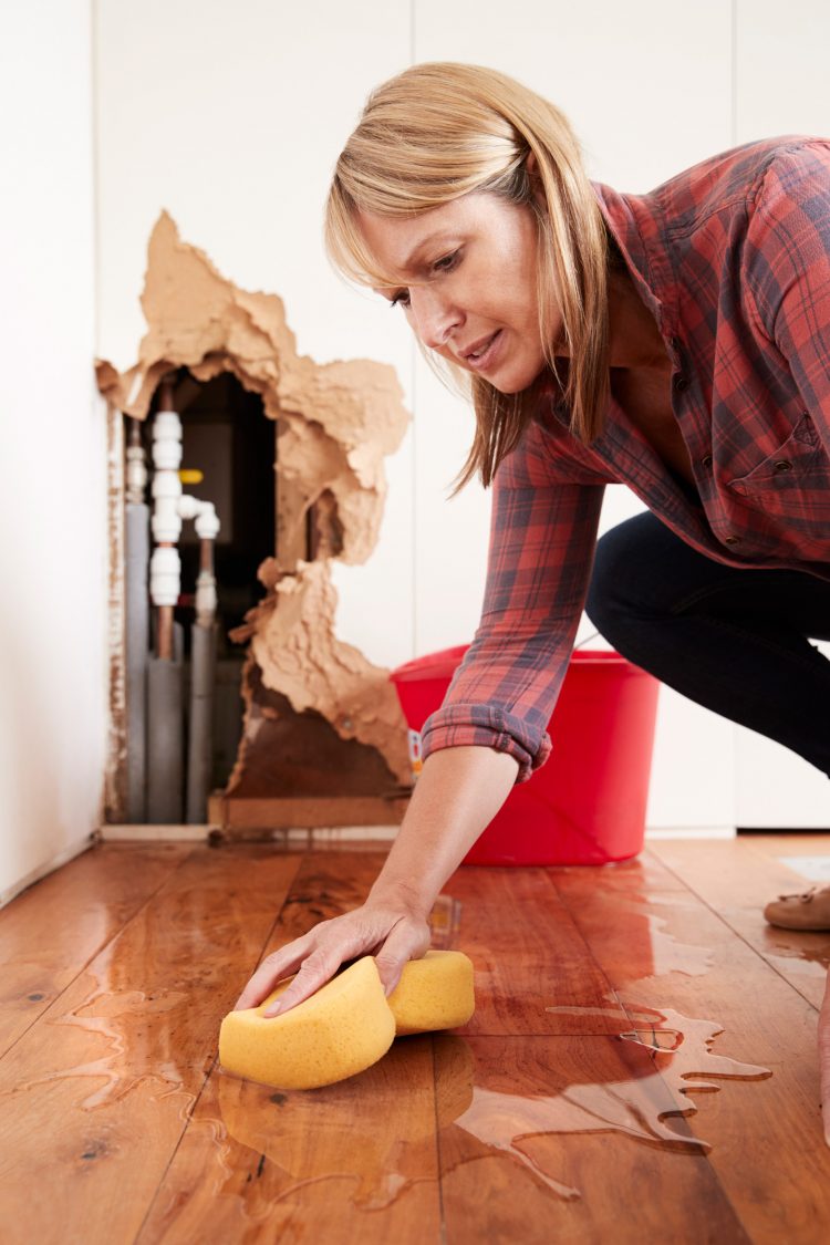 Woman cleaning up water damage from a burst pipe