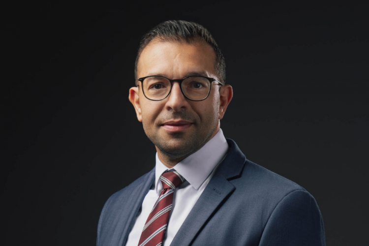 Photo of the business owner in a blue suit and red tie