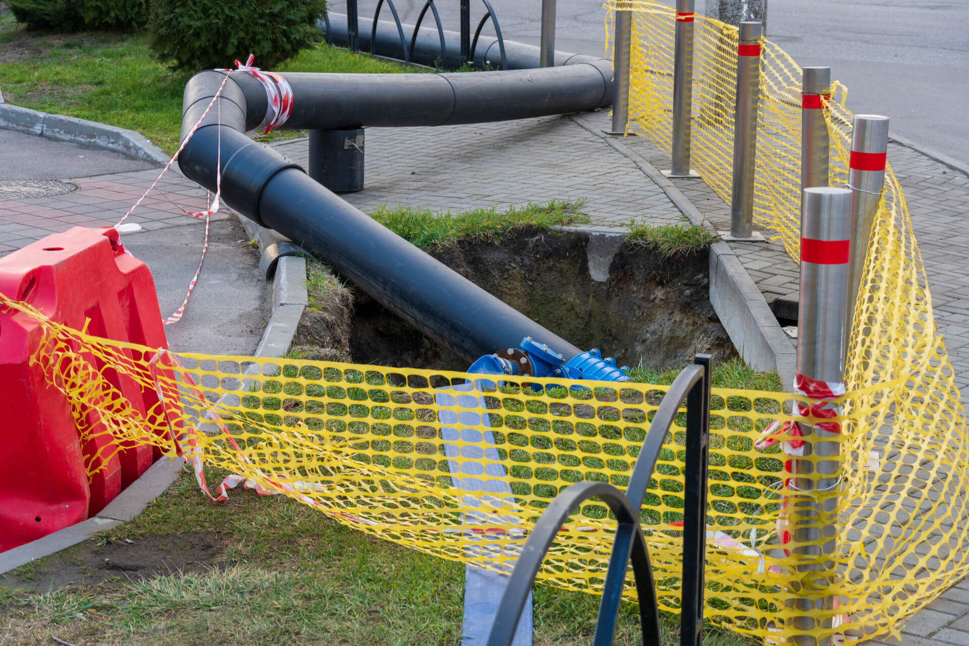 A water pipeline under repair at an urban site with safety barriers.