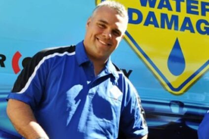 Two Happy 1-800 water damage employees standing outside in front of a company truck