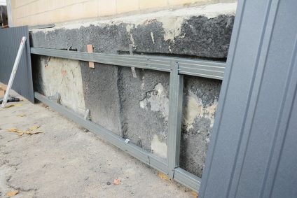 House foundation wall repair, renovation with installing metal sheets on metal frame for waterproofing and protect from rain wetness.