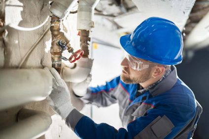 A technician inspecting plumbing pipes