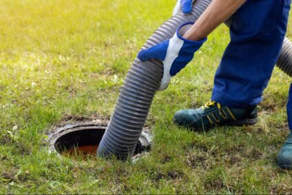 Septic tank professional inspecting a pump system in a residential yard to prevent sewage backup.