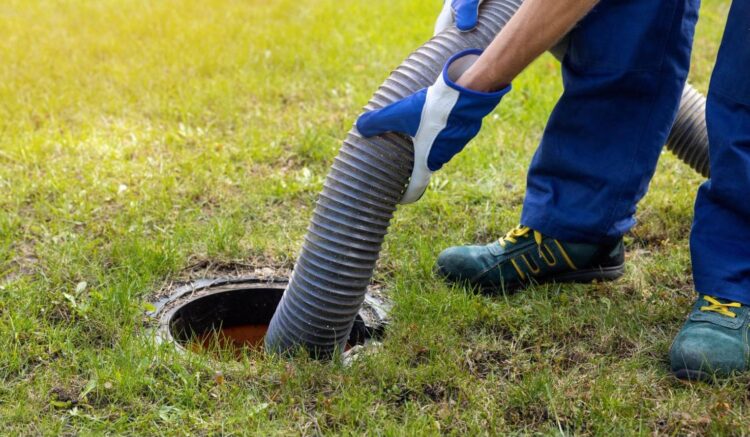 Septic tank professional inspecting a pump system in a residential yard to prevent sewage backup.